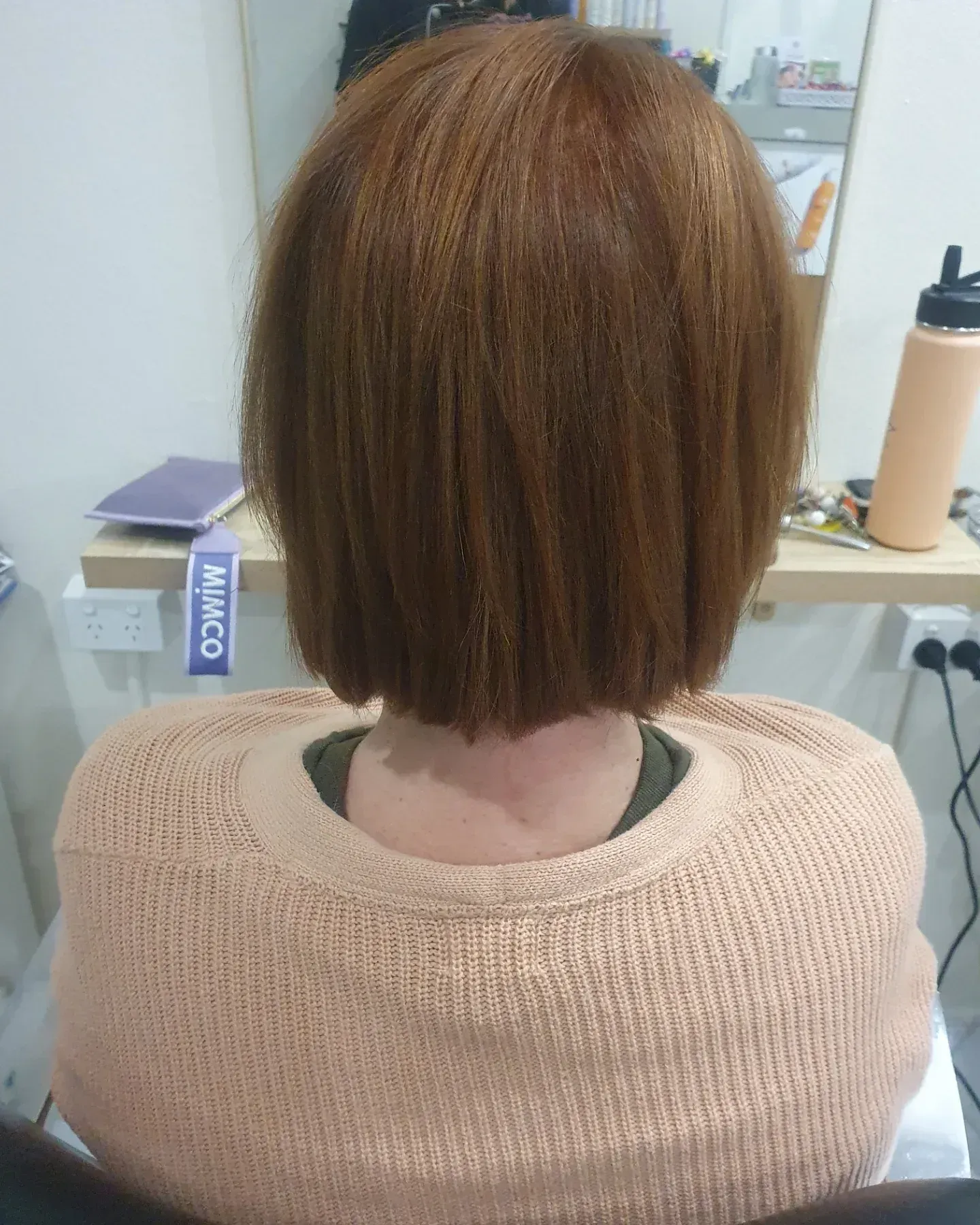 Person With Brown Hair in a Bob Haircut Wearing a Light Pink Sweater in a Salon — ClaireAbella Hair Studio In Kariong, NSW