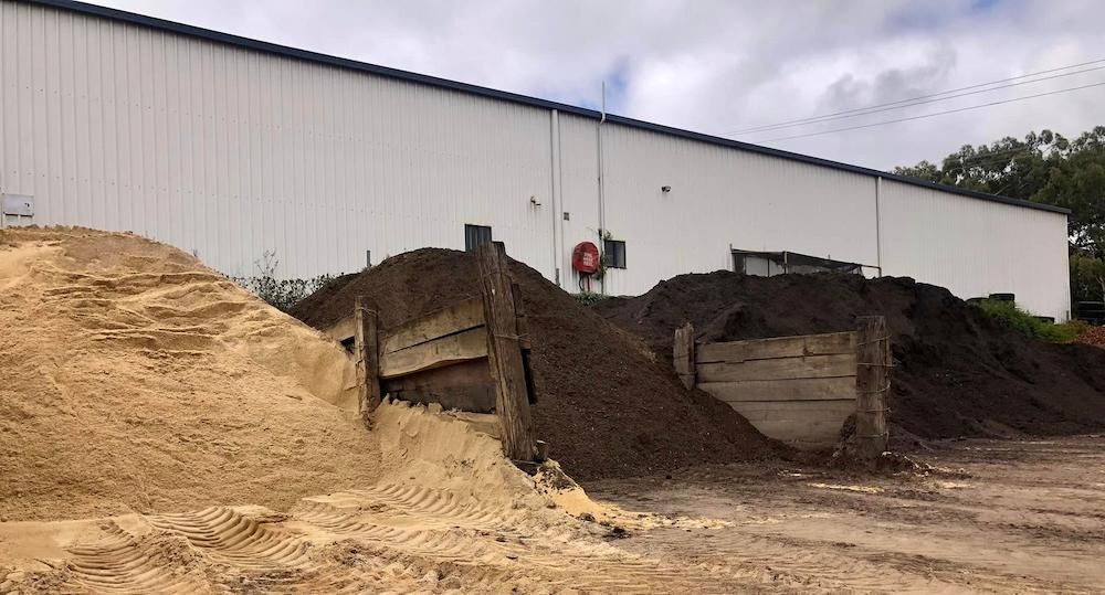 A Pile of Dirt and Sand is Sitting in Front of a Building — Highfields Landscape Supplies In Crows Nest, QLD