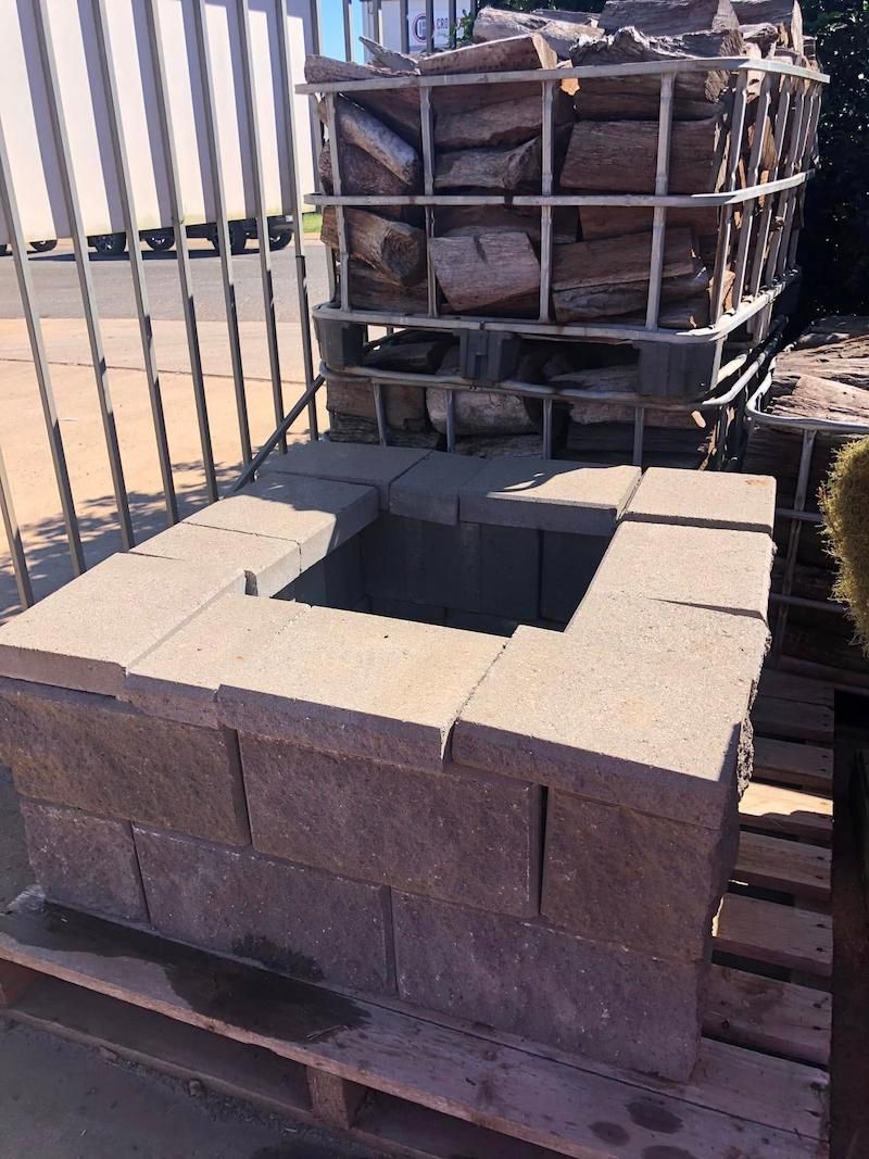 A Brick Planter is Sitting on a Wooden Pallet Next to a Basket of Logs — Highfields Landscape Supplies In Crows Nest, QLD