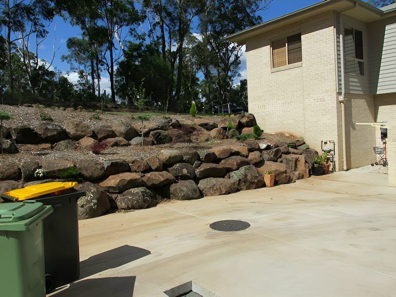 A House With a Large Rock Wall in Front of It — Highfields Landscape Supplies In Meringandan, QLD