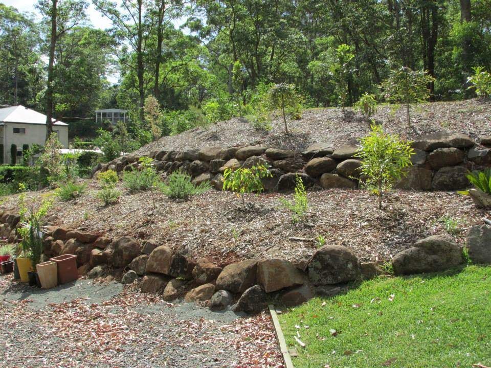 A Lush Green Hillside With Rocks and Trees in the Background — Highfields Landscape Supplies In Meringandan, QLD