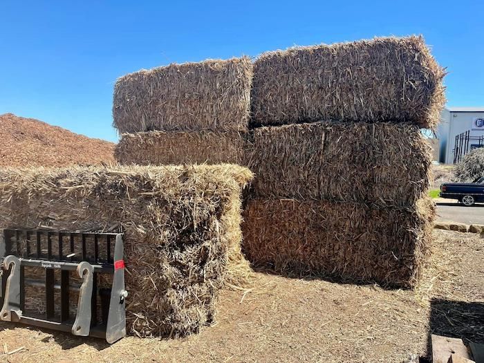 A Bunch of Hay Bales Are Stacked on Top of Each Other in a Field — Highfields Landscape Supplies In Crows Nest, QLD