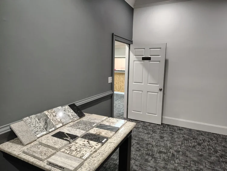 Samples of stone sit on a table in a room with a doorway and a white door.