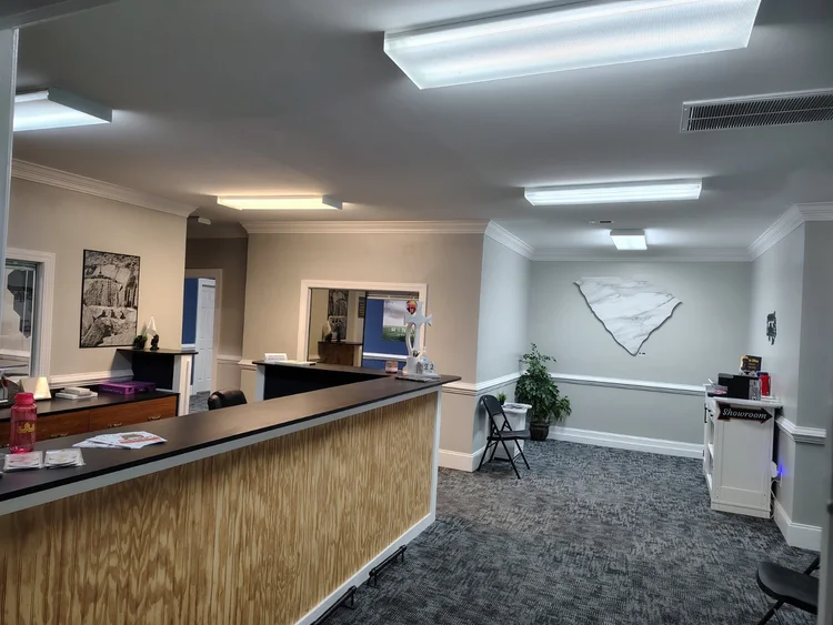 Interior of a business office with a reception desk, gray walls, and fluorescent lighting.