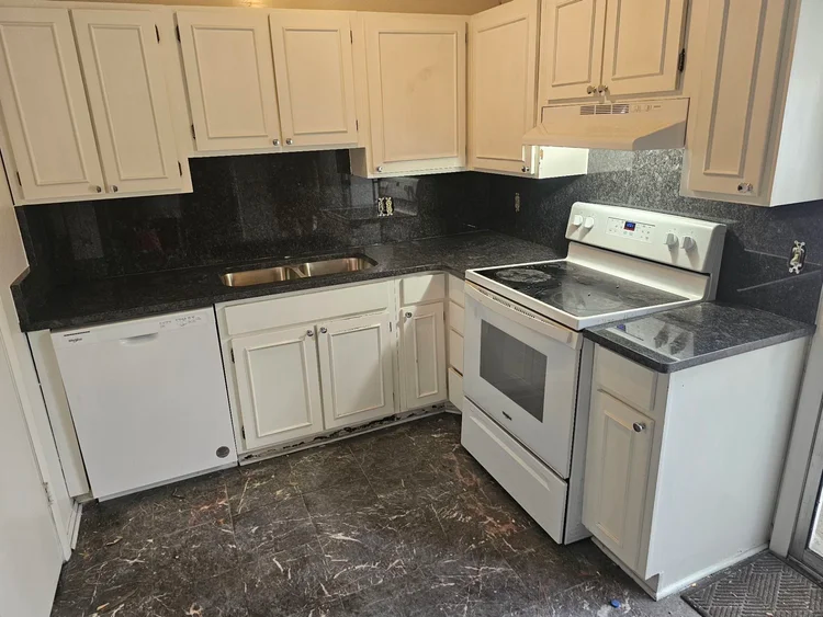 Kitchen with white cabinets, black countertops, and a white stove.