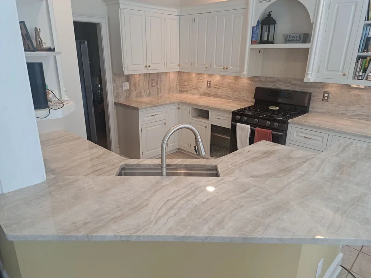 Cream-colored kitchen with granite countertops, white cabinets, and stainless steel sink.