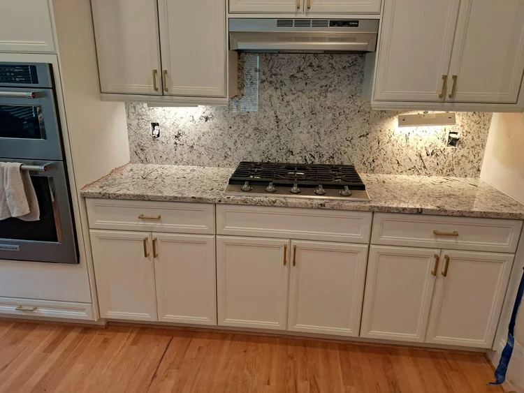 Kitchen with white cabinets, granite countertop, stove, and a stainless steel oven.