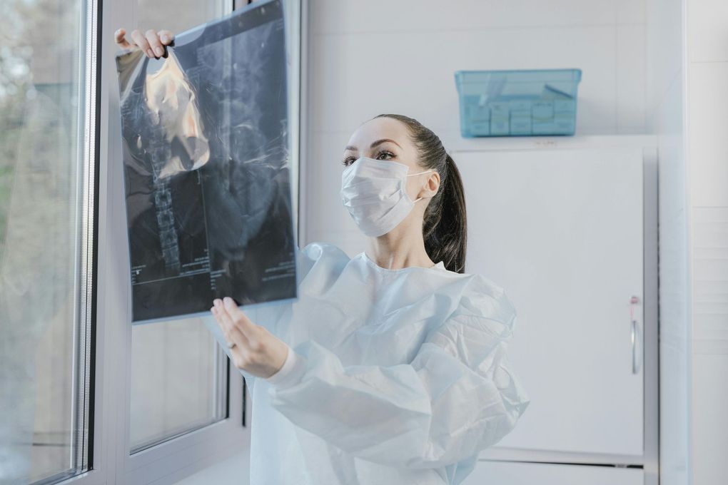 A female doctor wearing a mask is looking at an x-ray.