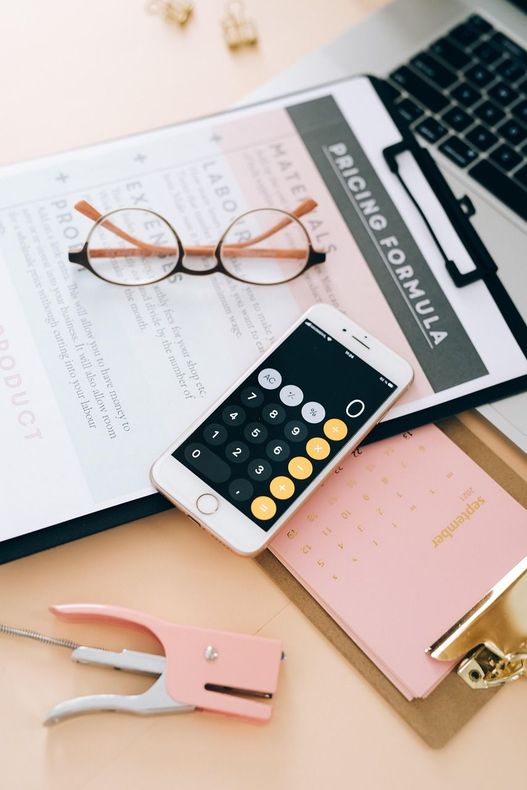 A cell phone sitting on top of a clipboard next to a pair of glasses.