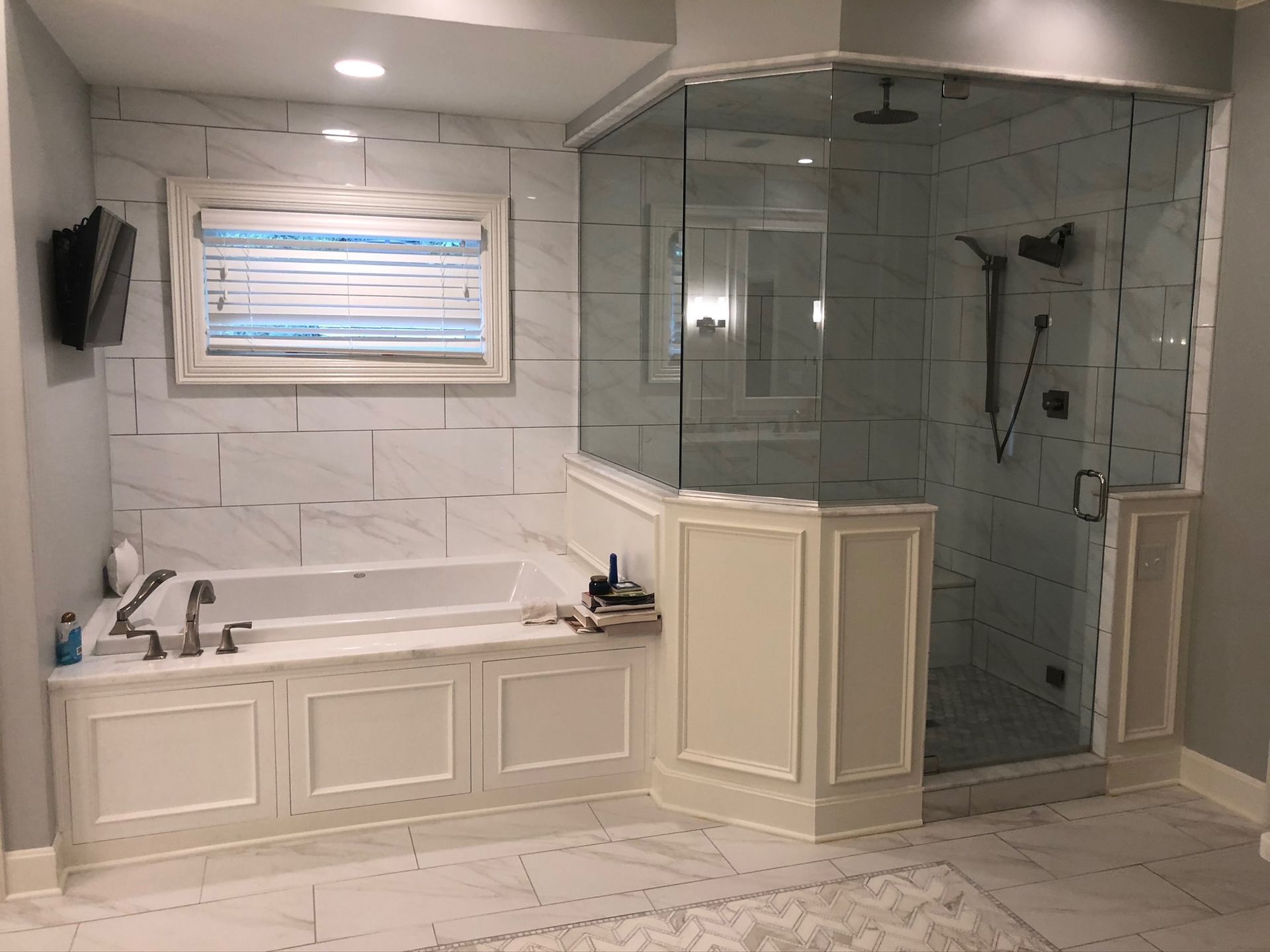 A bathroom with a tub , shower , and window.