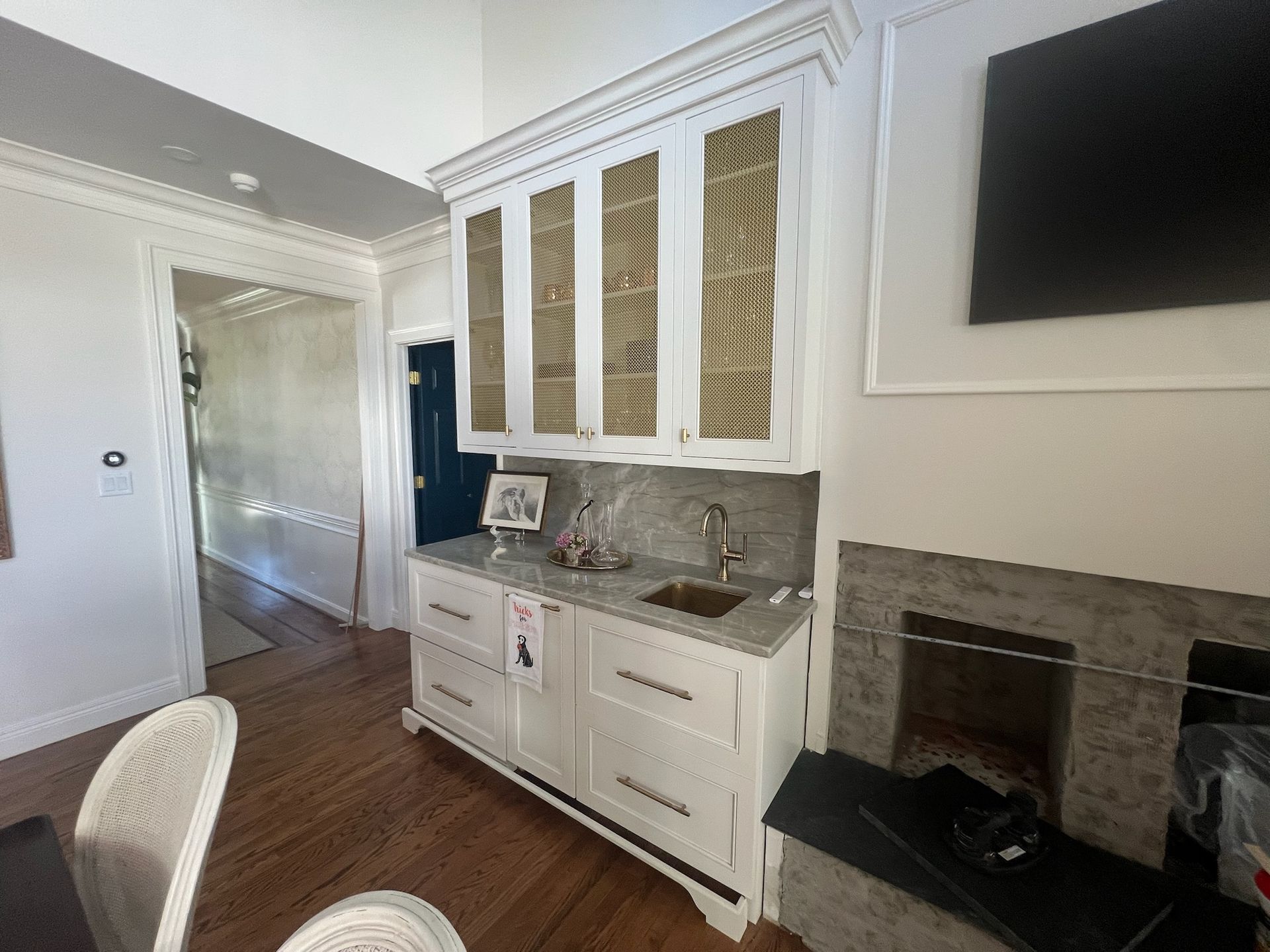 A kitchen with white cabinets , a sink , and a fireplace.