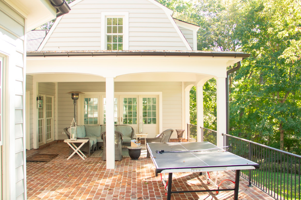 There is a ping pong table on the porch of a house.