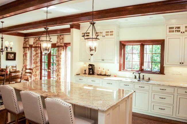 A kitchen with white cabinets , granite counter tops , and a large island.