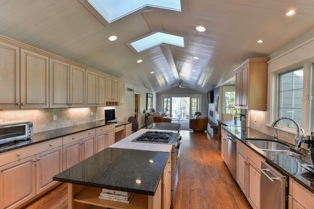 A kitchen with a large island in the middle and a skylight on the ceiling.