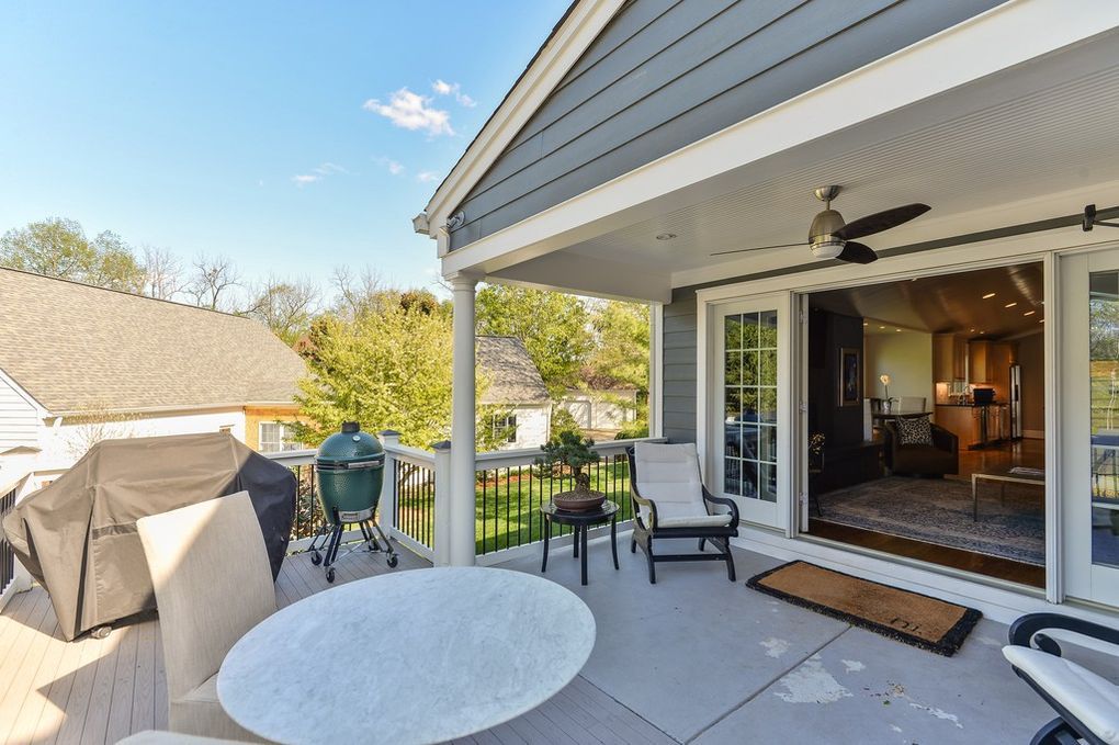 A patio with a table , chairs , a grill and a ceiling fan.
