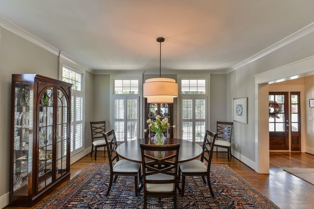 A dining room with a round table and chairs and a rug.