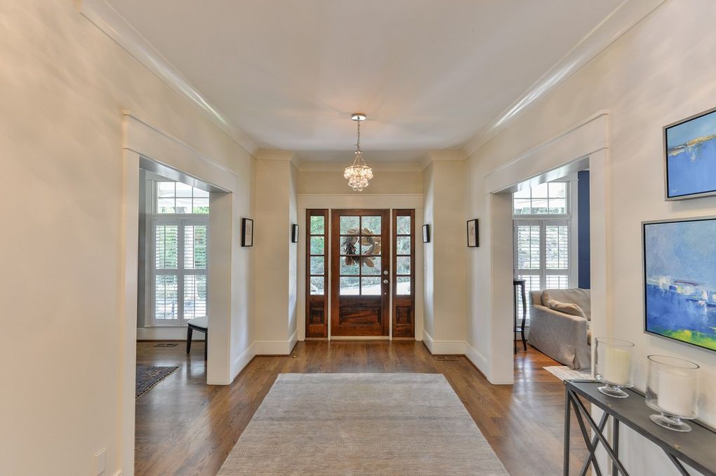 A large hallway in a house with a wooden door and a rug.