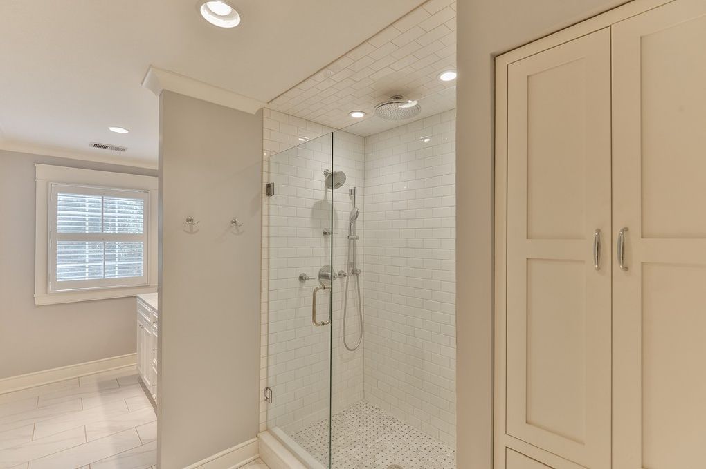 A bathroom with a walk in shower and a window.