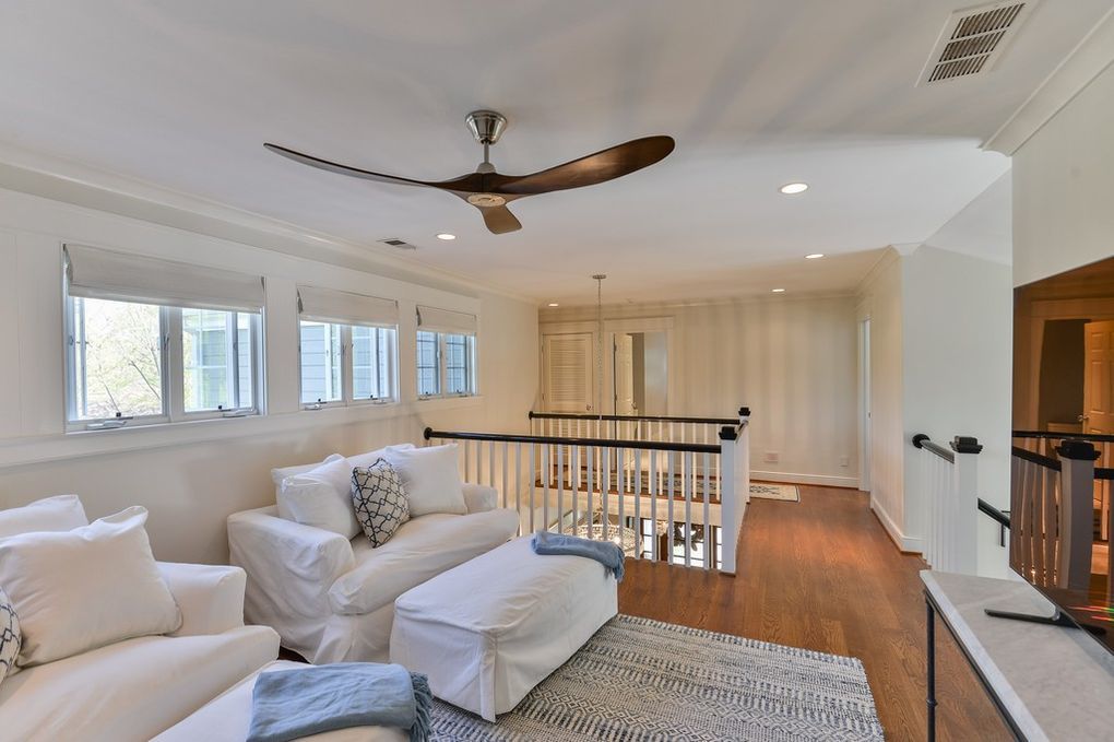A living room with white furniture and a ceiling fan
