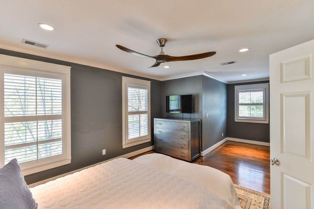 A bedroom with a large bed , a ceiling fan , and a television.