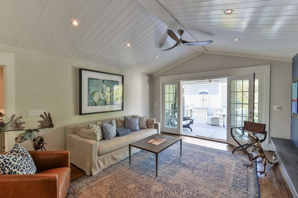 A living room with a couch , chair , coffee table and ceiling fan.