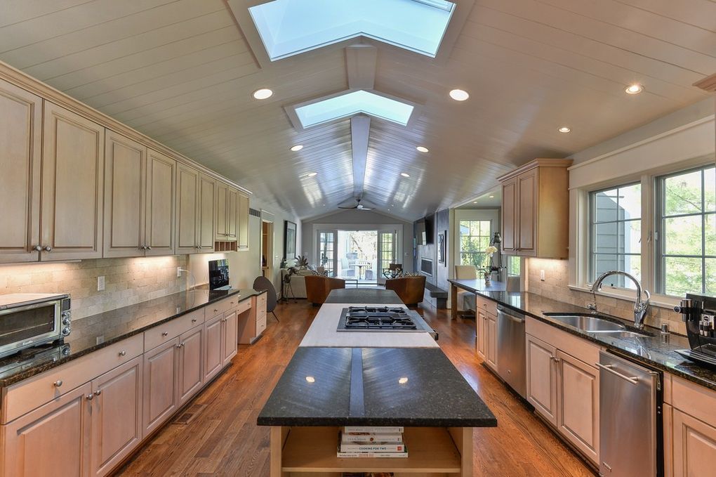 A kitchen with a large island in the middle and a skylight on the ceiling.