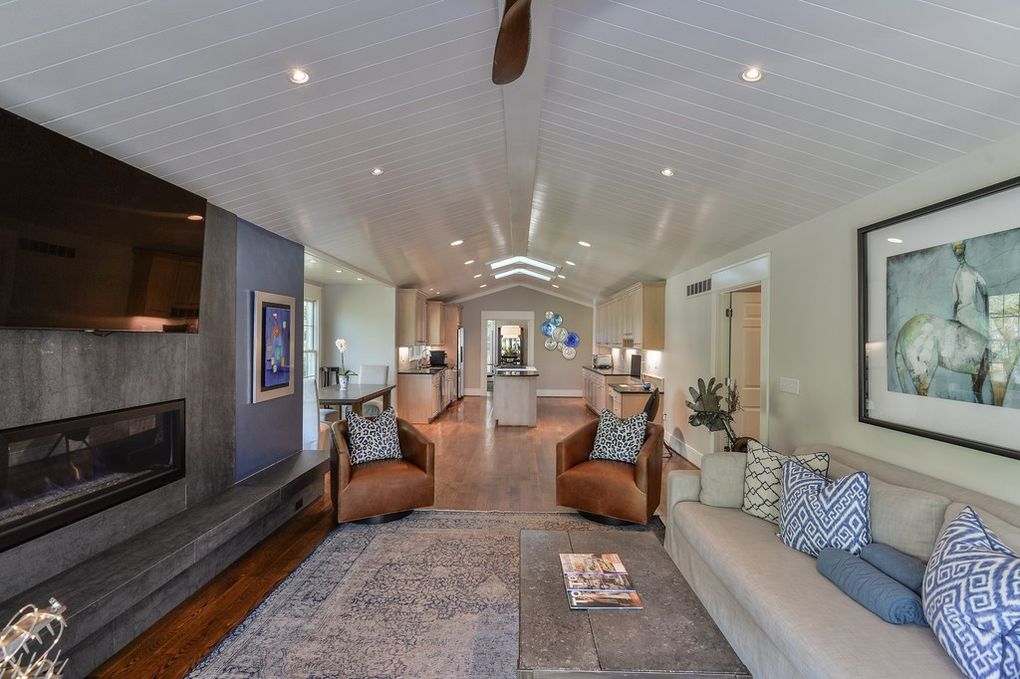 A living room with a couch , chairs , fireplace and television.