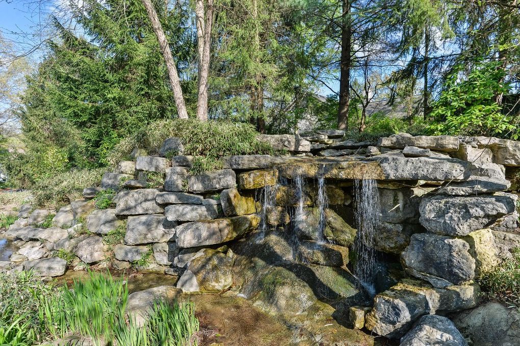 A waterfall is surrounded by rocks and trees in the middle of a forest.