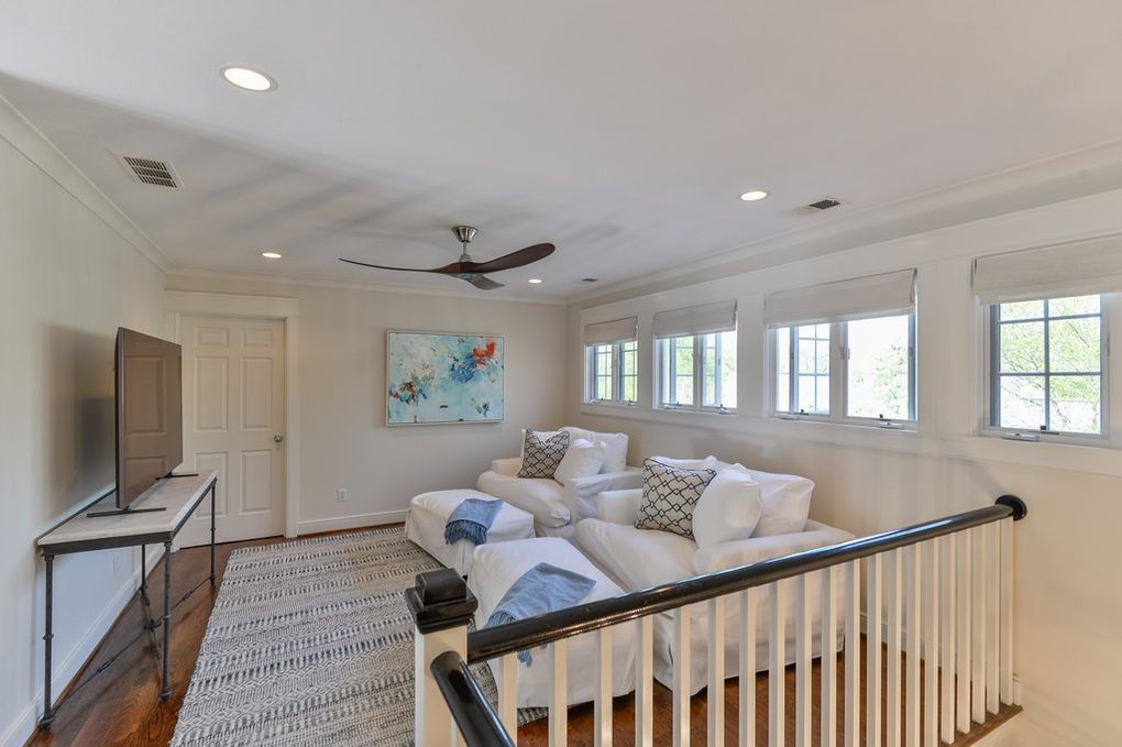 A living room with a couch , chairs , a television and a ceiling fan.