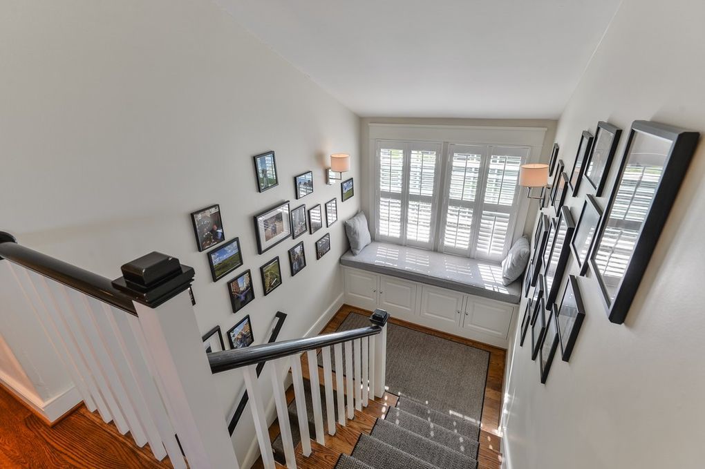 A staircase with a window seat and a wall filled with pictures.