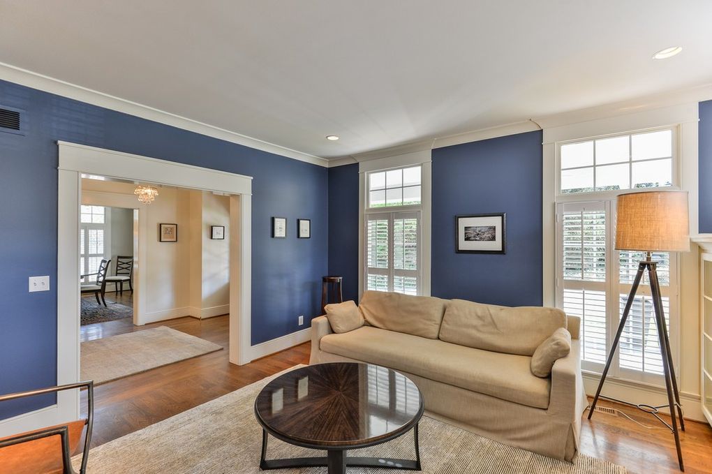 A living room with blue walls , a couch , a coffee table and a lamp.