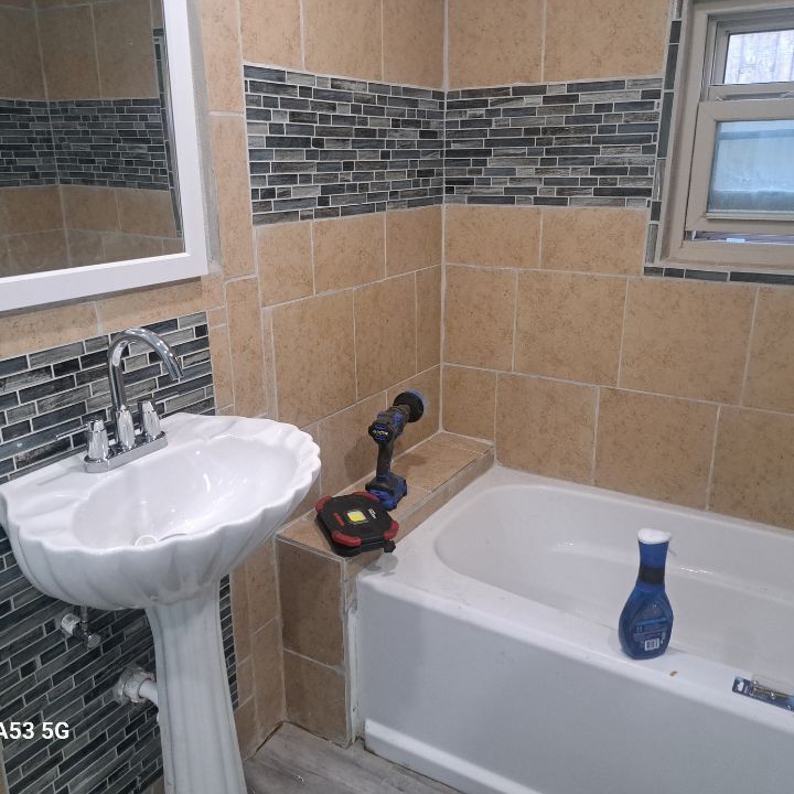 A renovated bathroom with a sink , tub and mirror