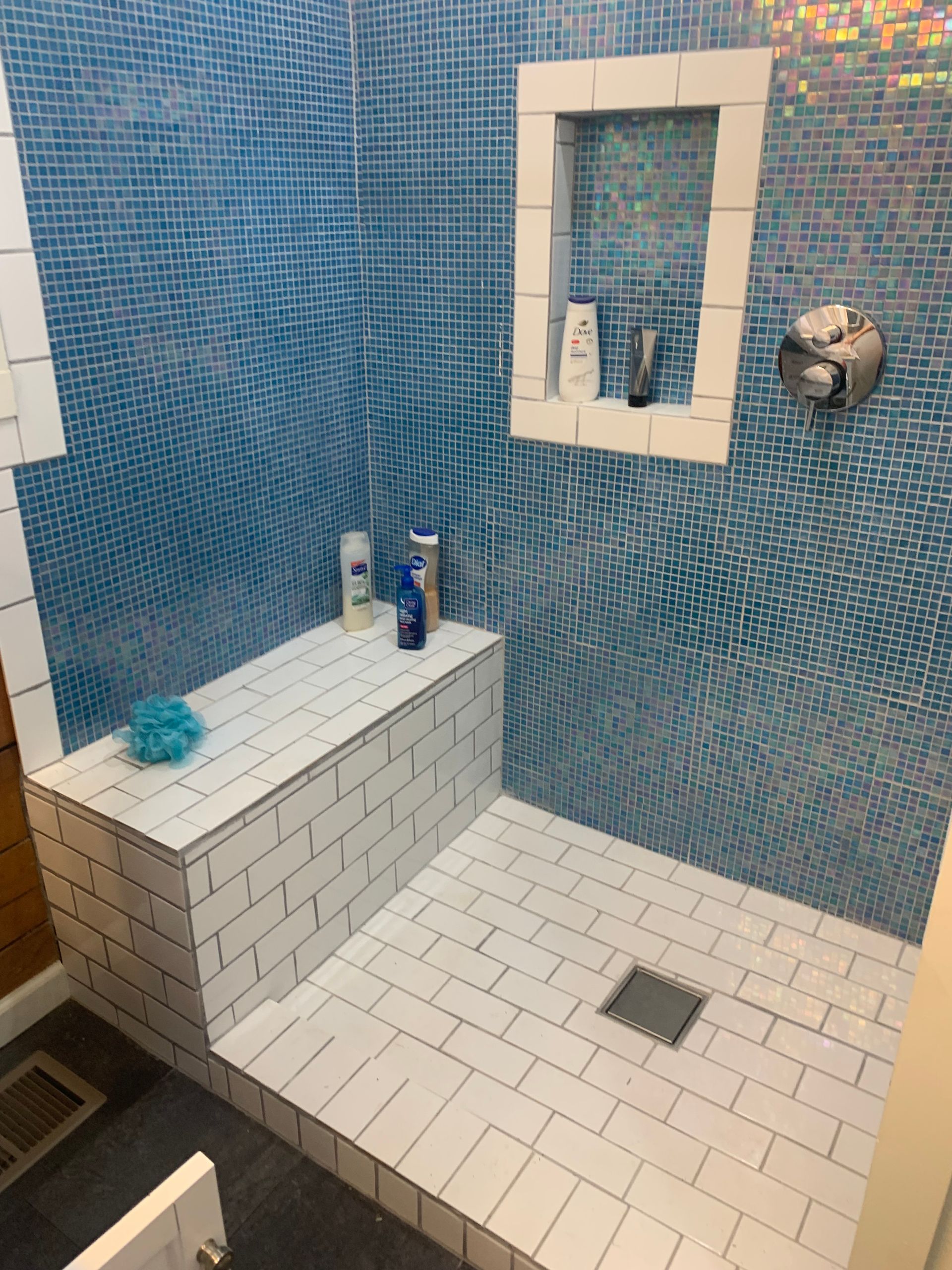 A renovated bathroom with a walk in shower and a bench.