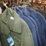 Racks of hanging green and blue coats in a store display