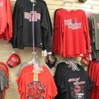Display of red and black graphic T-shirts hanging on a wall in a store.