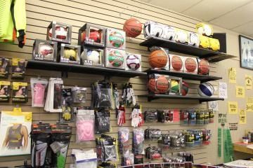 Display of sports equipment on wall racks, with colorful bags and packaged items in rows.