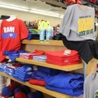 T-shirts and folded sweatshirts displayed on store shelves, with colorful apparel in the background