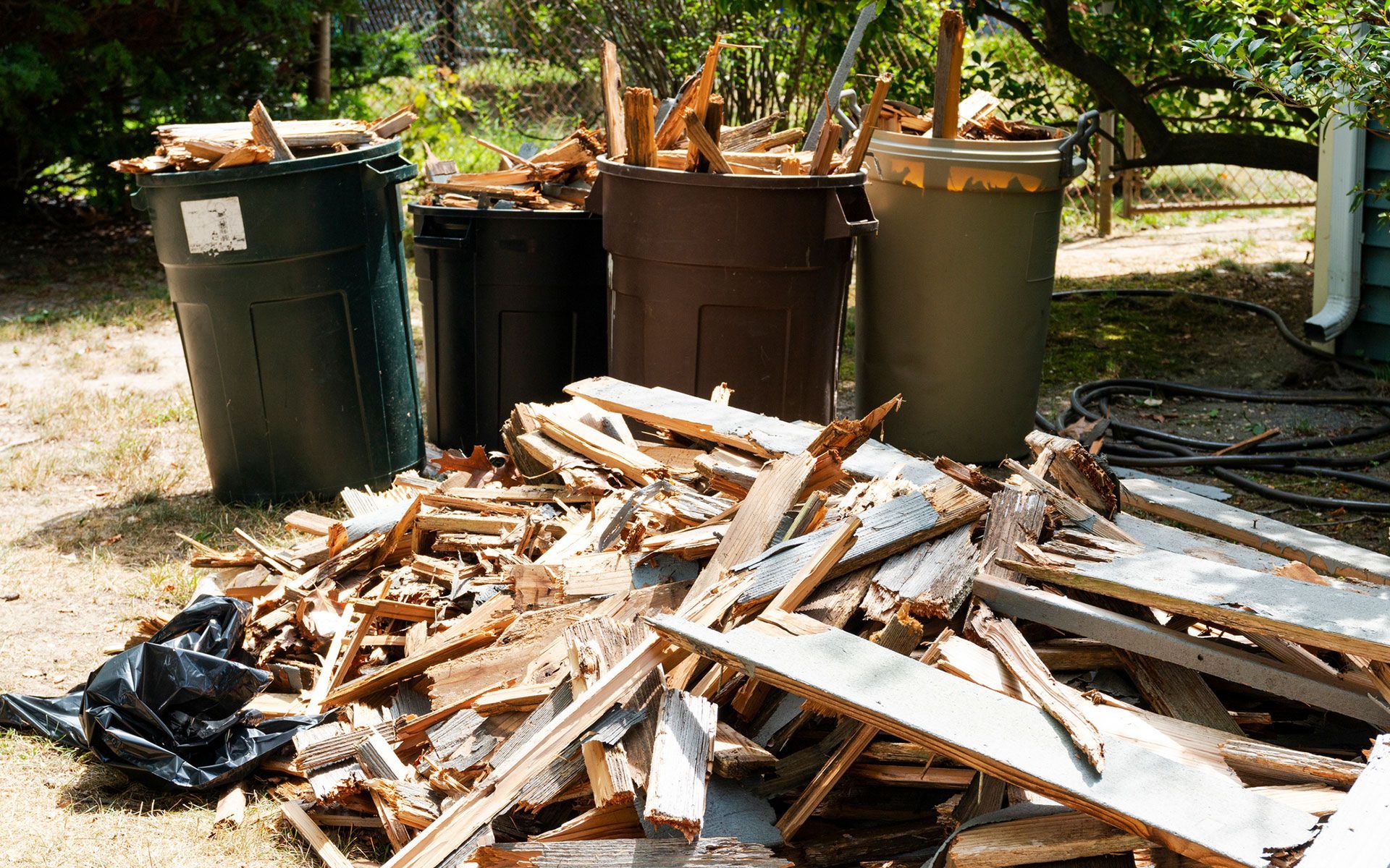A pile of wood and trash cans in a yard