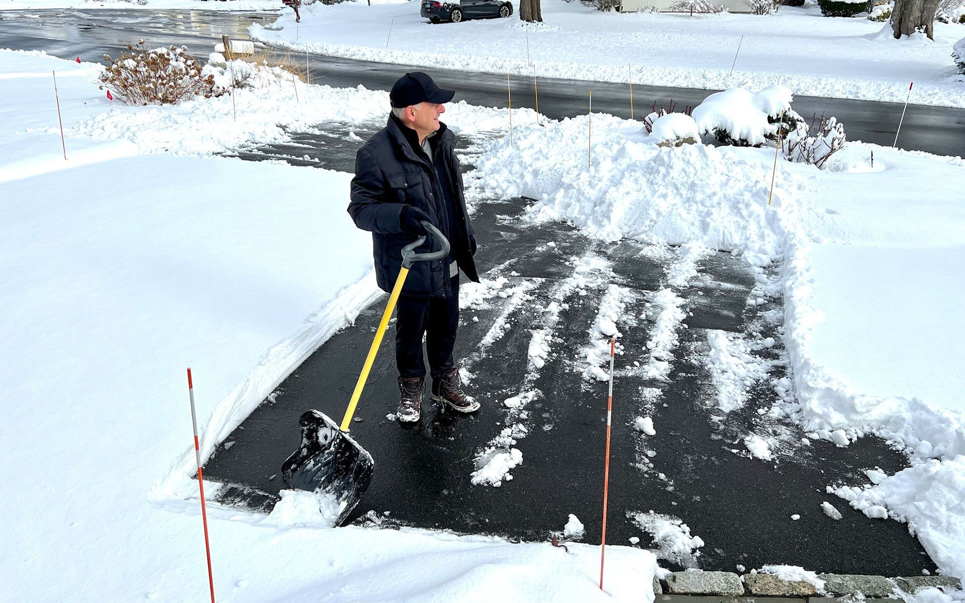A man is clearing snow from a driveway with a shovel.