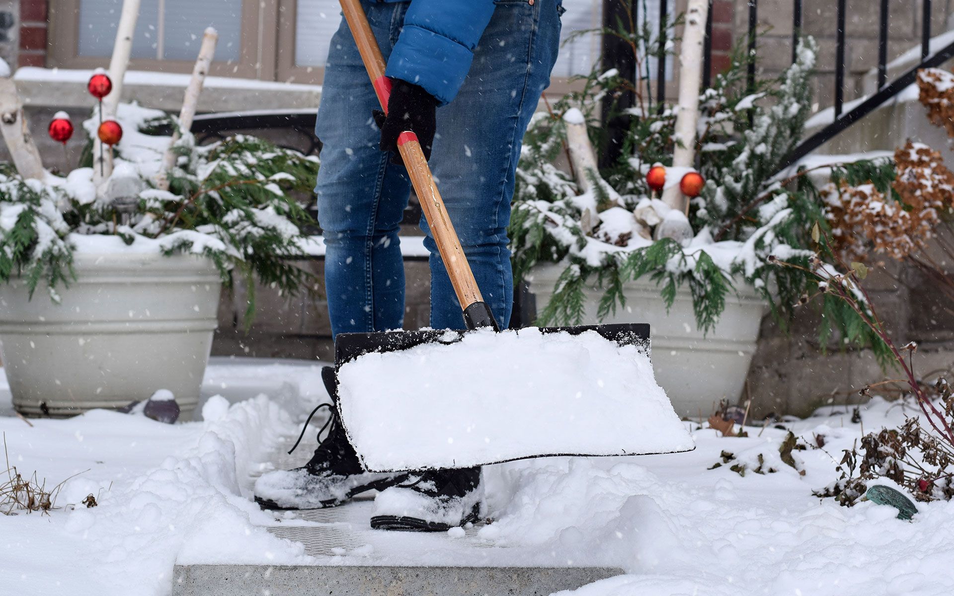A person is shoveling snow on a sidewalk in front of a house.