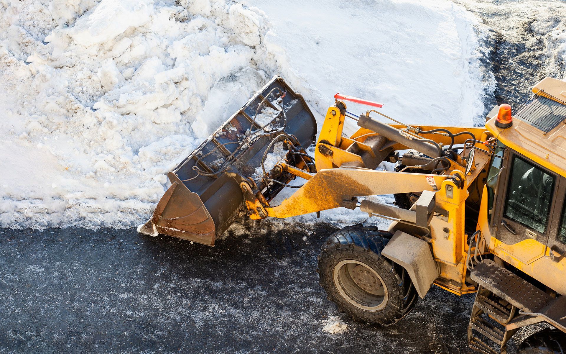 A yellow bulldozer is clearing snow from the road.
