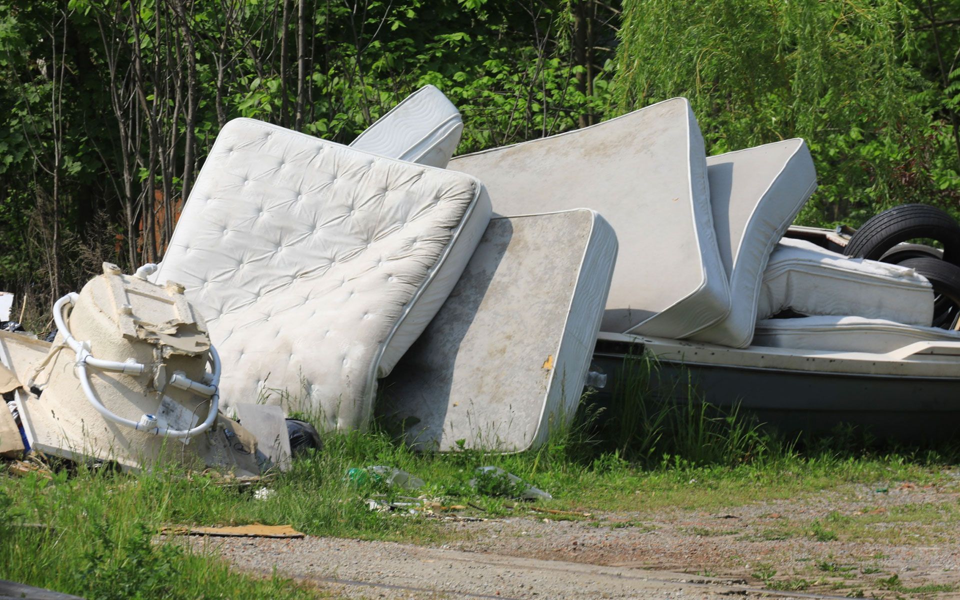 A pile of mattresses and tires in a grassy field