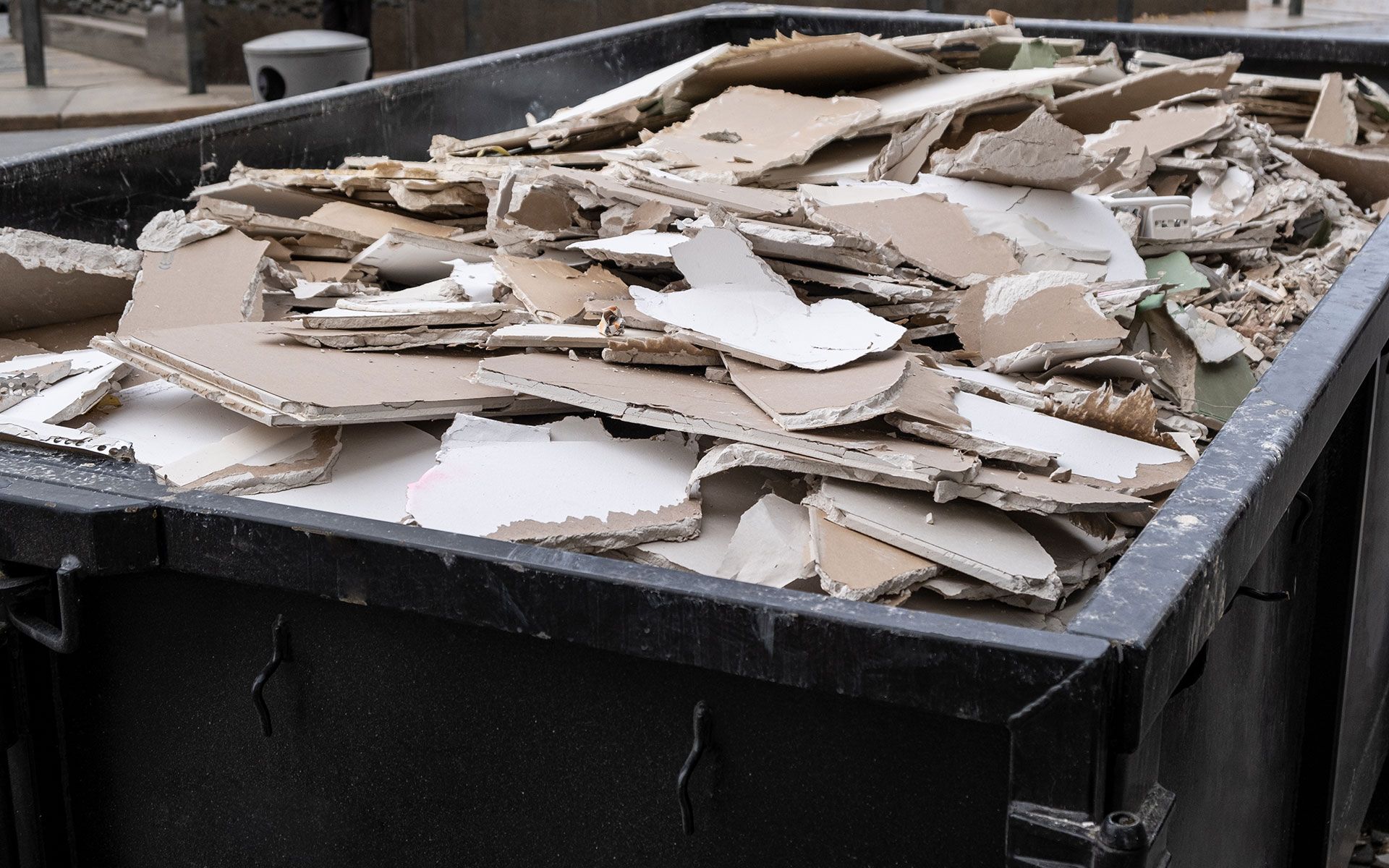 A dumpster filled with a lot of cardboard pieces.