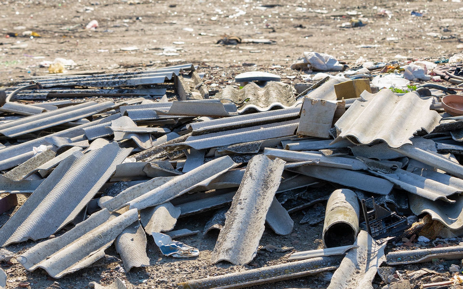 A pile of roofing shingles is laying on the ground.