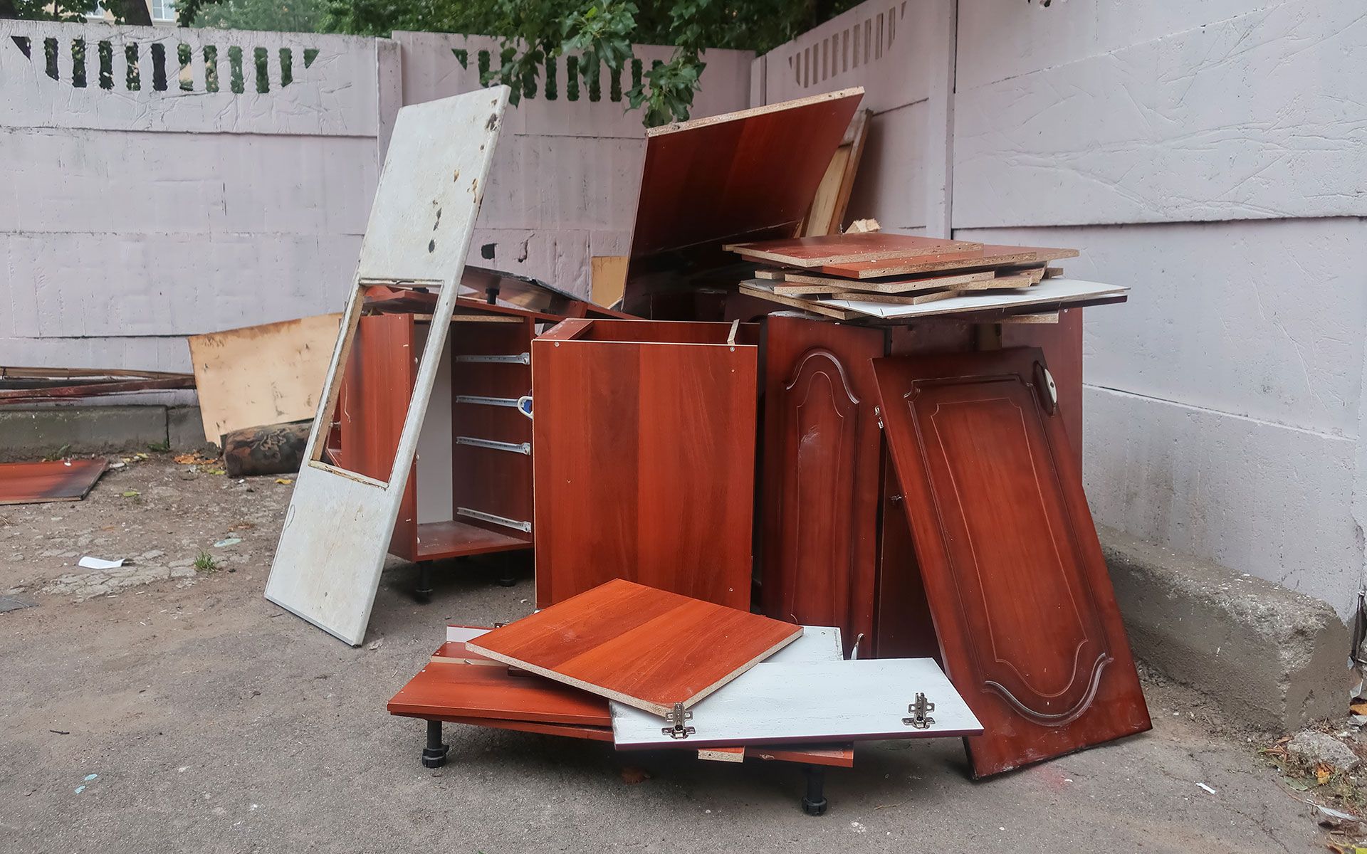 A pile of wood is sitting on the ground in front of a fence.