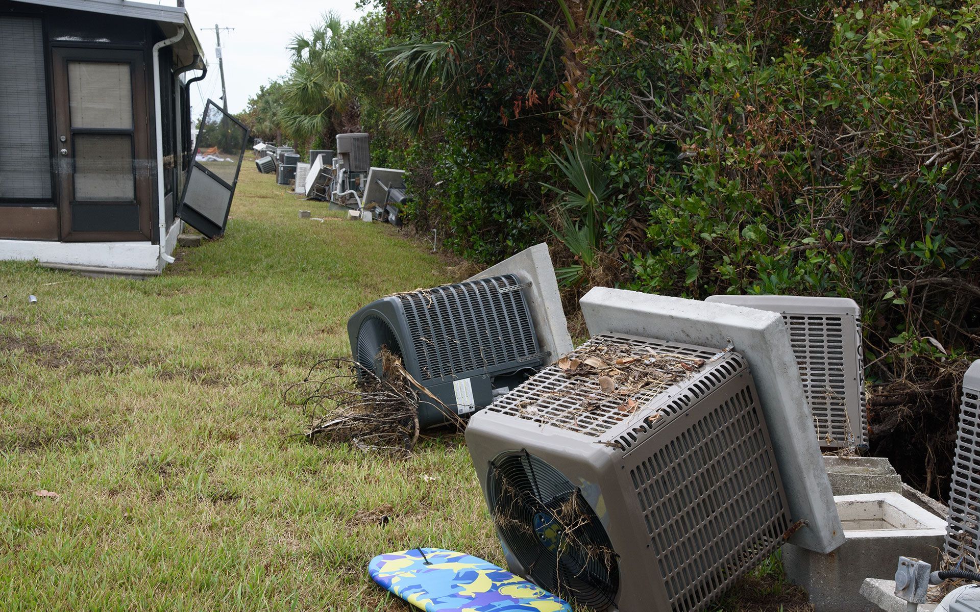 A bunch of trash is laying on the grass in front of a house.