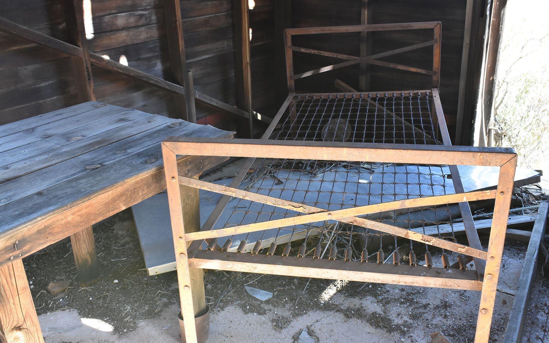 An old wooden bed frame is sitting in a wooden shed.