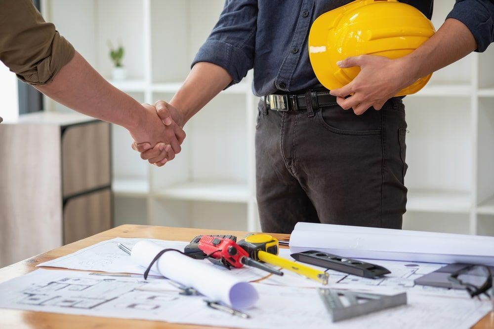 A man wearing a hard hat is shaking hands with another man.