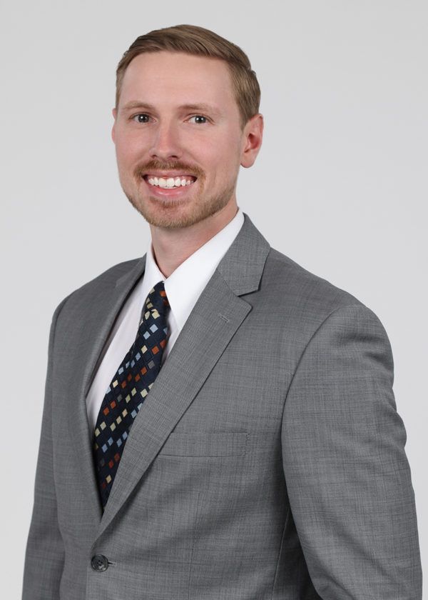 A woman in a black sweater is standing with her arms crossed and smiling.
