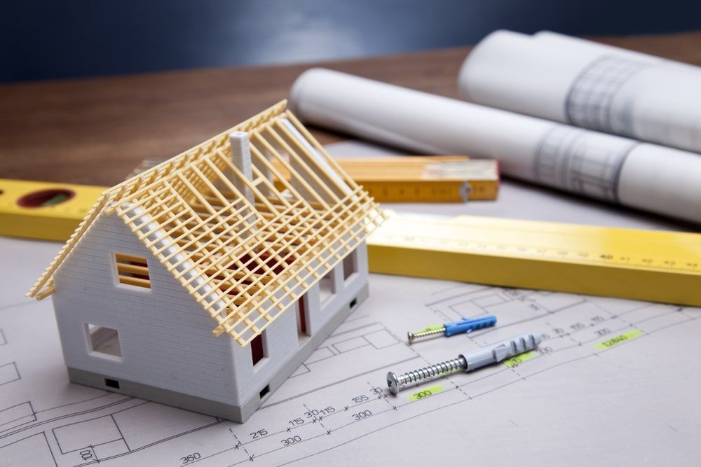 A model house is sitting on top of a blueprint on a table.